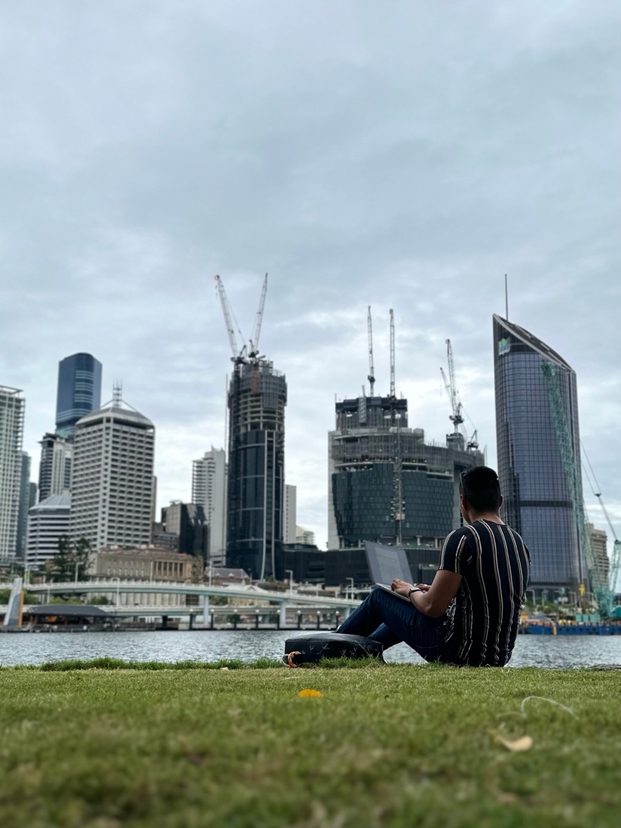 Zach with laptop in front of the Brisbane skyline